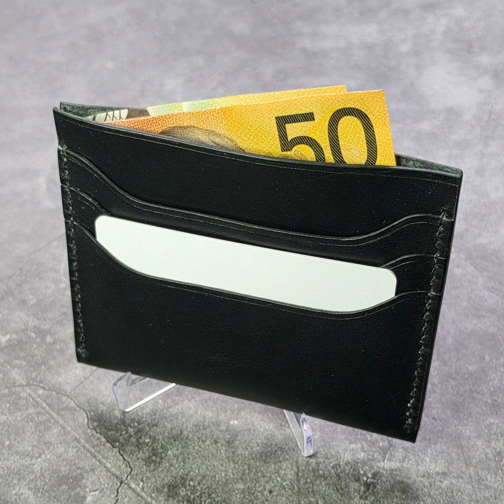 Black leather wallet with a card and 50 euro bill on a gray surface