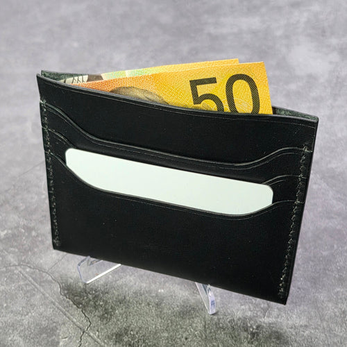 Black leather wallet with a card and 50 euro bill on a gray surface